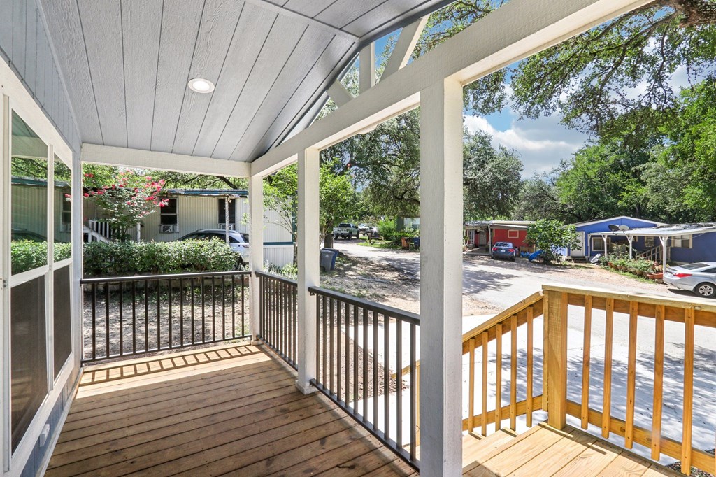 A balcony with a white railing and wooden floor.