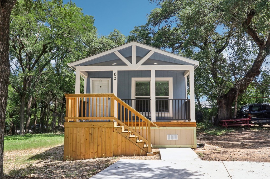 A small house with a porch and a staircase leading to the door.