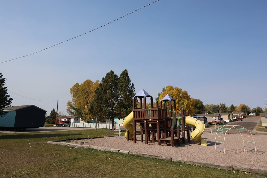 A playground with a yellow slide and a wooden structure.