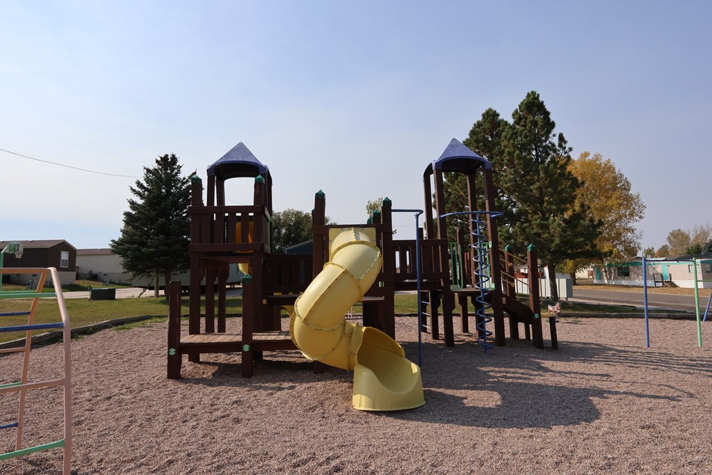 A playground with a yellow slide and wooden structures.