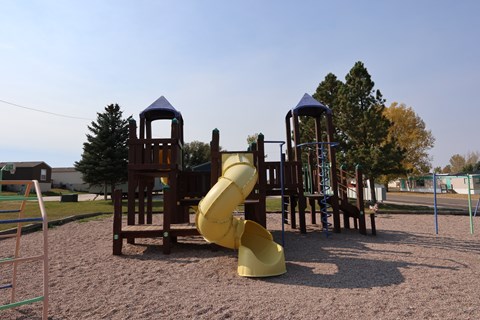 A playground with a yellow slide and wooden structures.