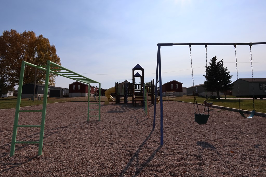 A playground with a swing set and a green ladder.