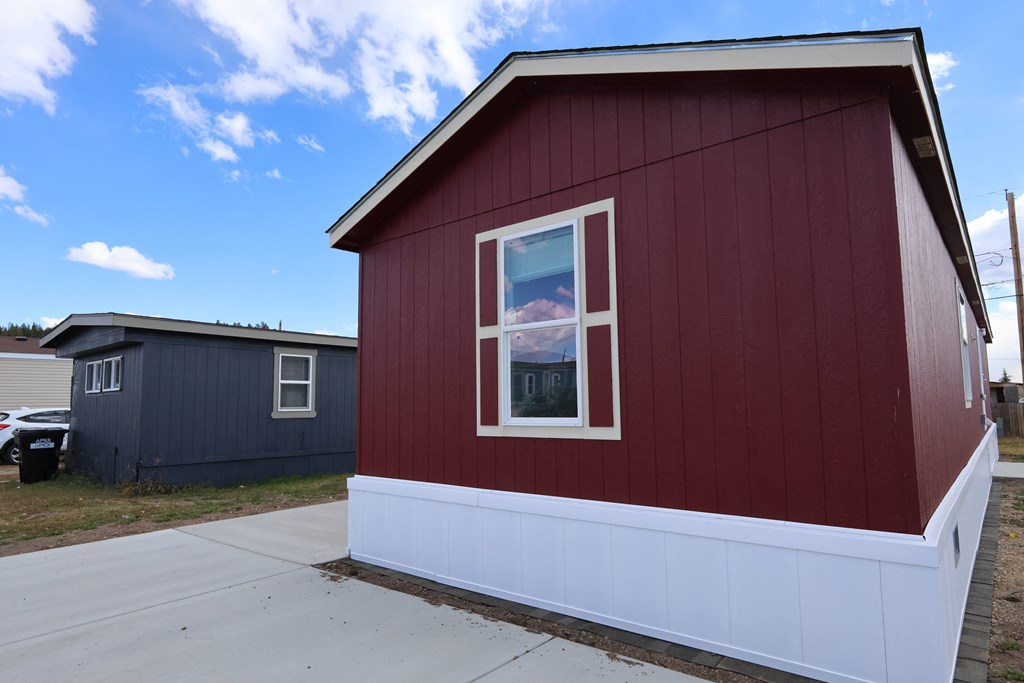 the side of a red building with a window and a sidewalk
