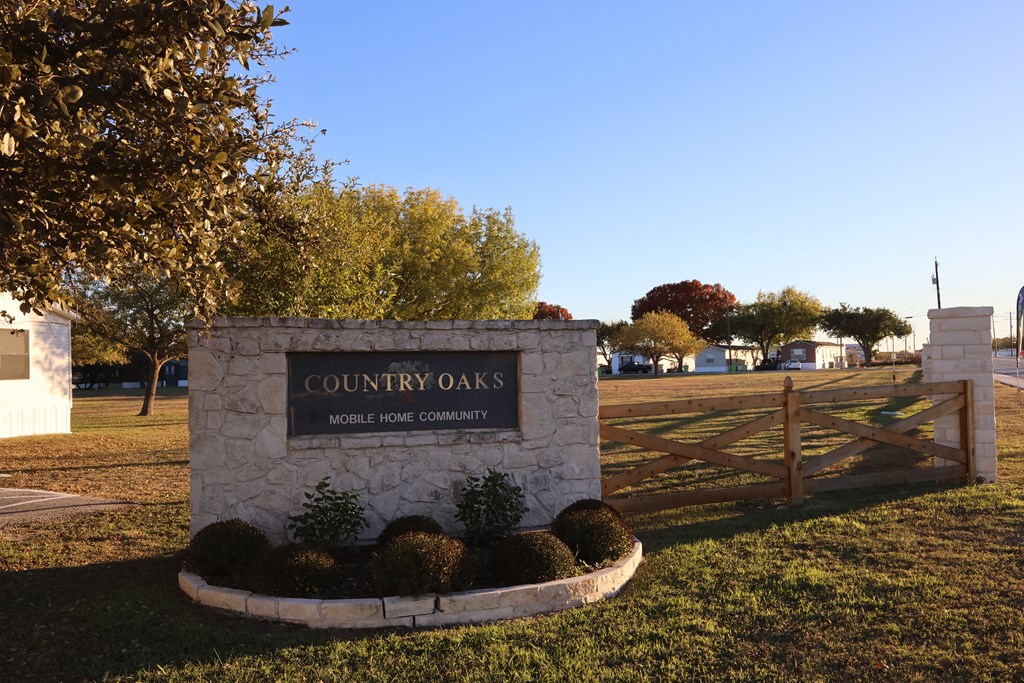 A stone sign that says "Country Oaks Mobile Home Community" stands in a grassy area.