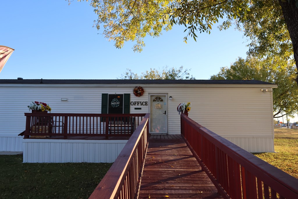 A small white building with a porch and a sign that says "OFFICE".