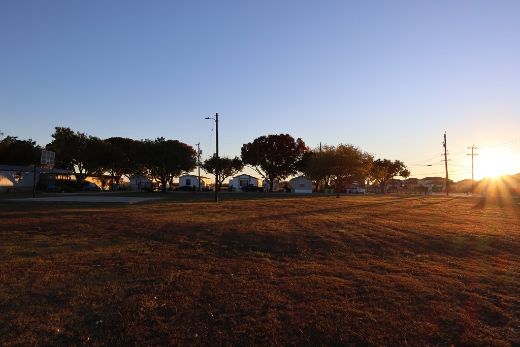 A sunset view of a field with houses and trees.