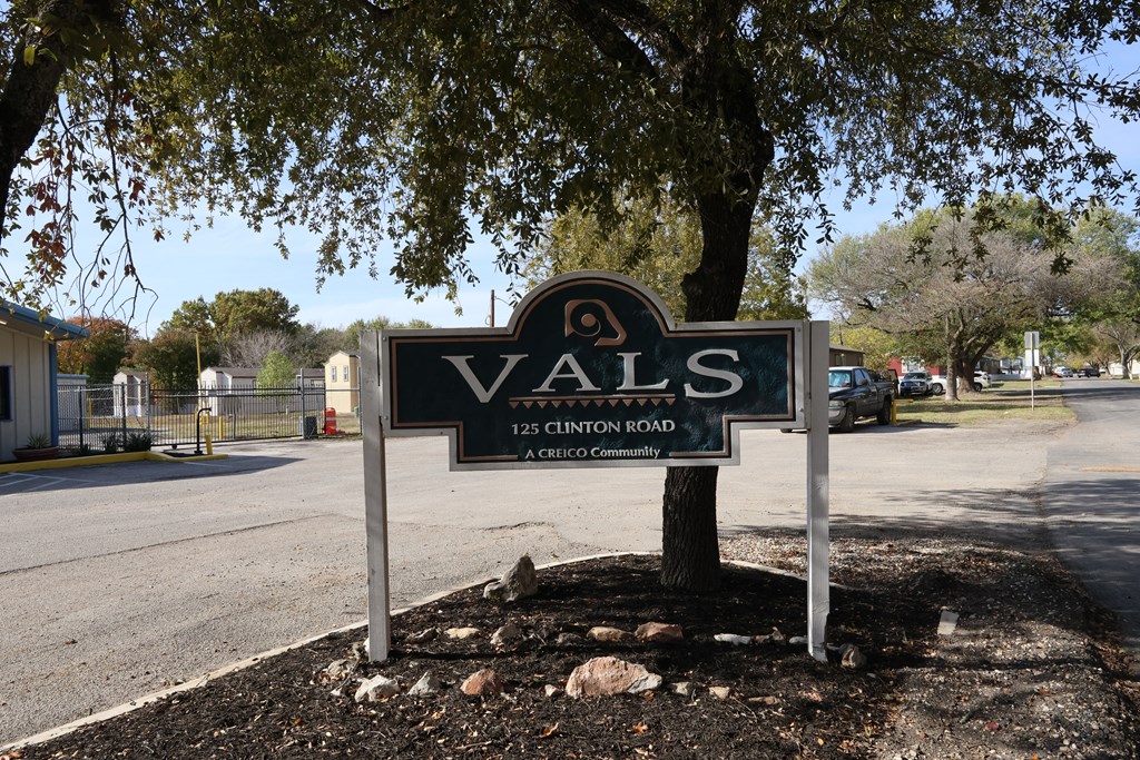 A sign for Vals community stands in front of a tree.