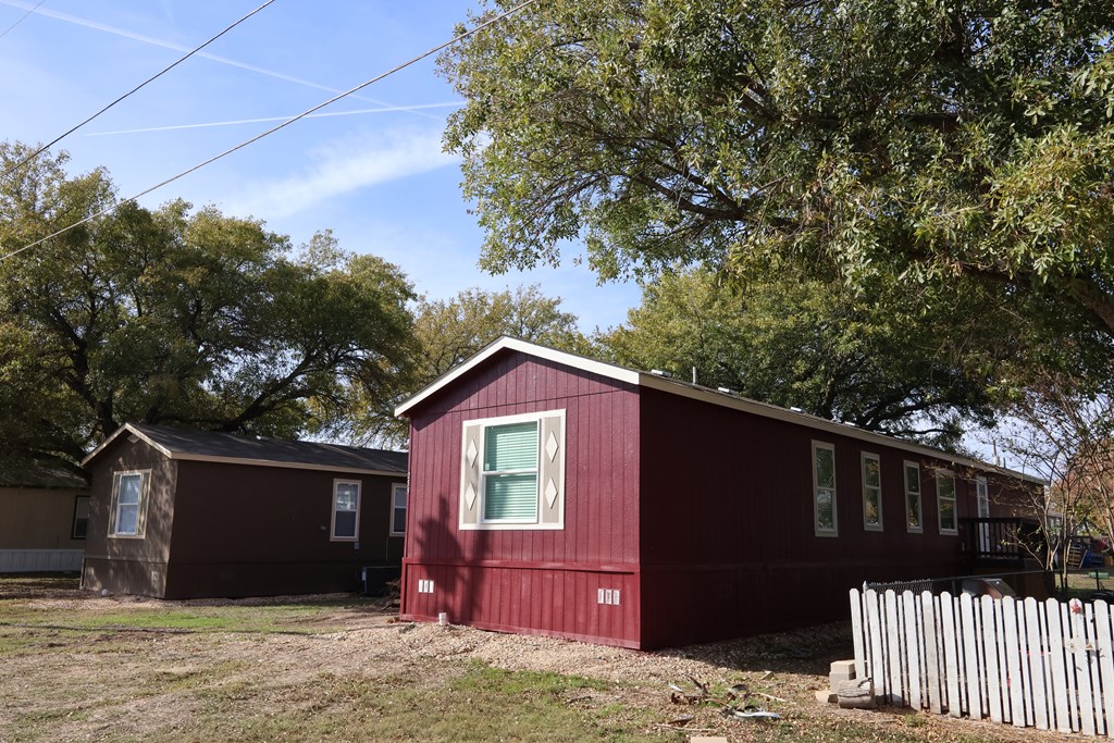 A red house with a white picket fence in front.