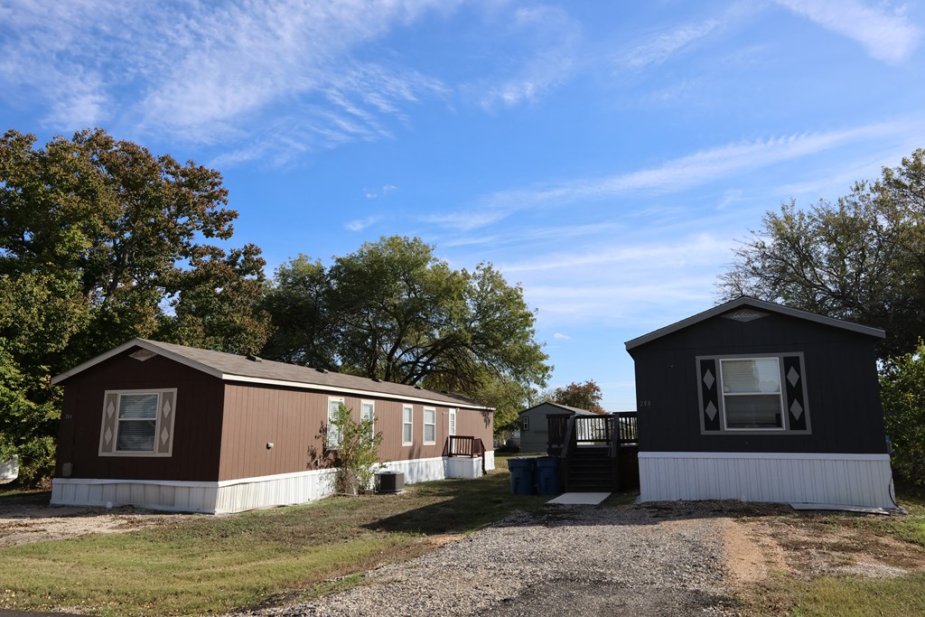 A brown and white mobile home sits in a grassy lot.
