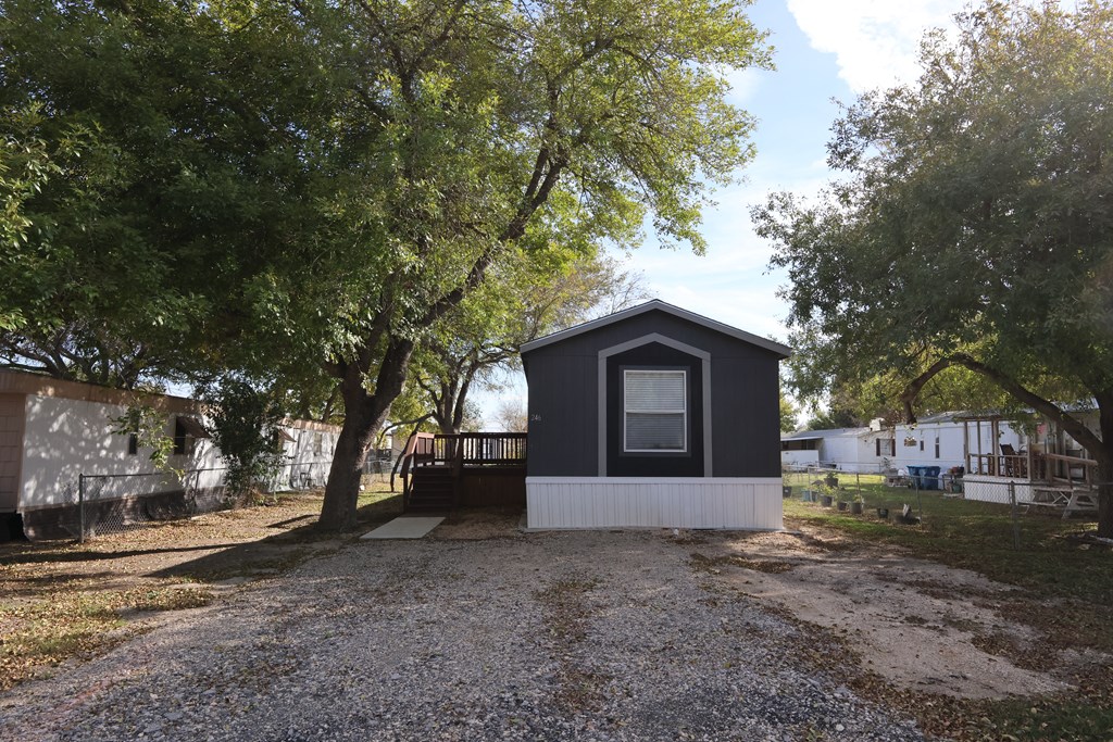 A small black and white house with a gravel driveway in front.