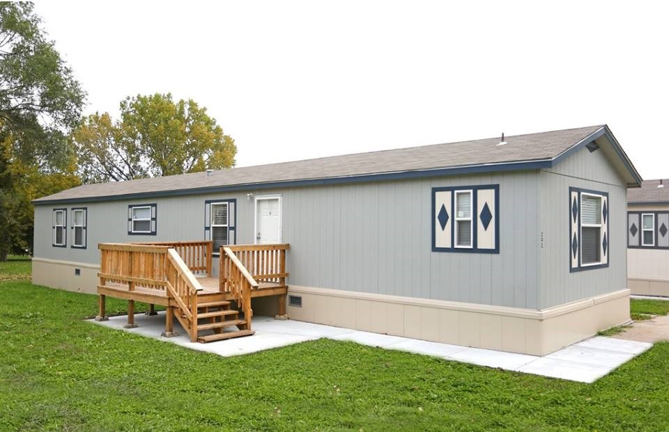 A grey house with a wooden deck in front.