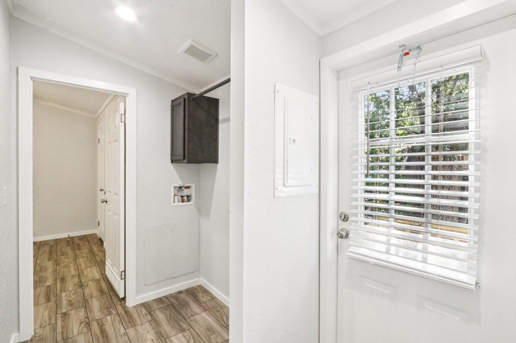 A white door with a window and a black box on the wall.