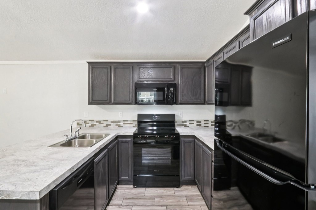 A modern kitchen with dark wood cabinets and stainless steel appliances.