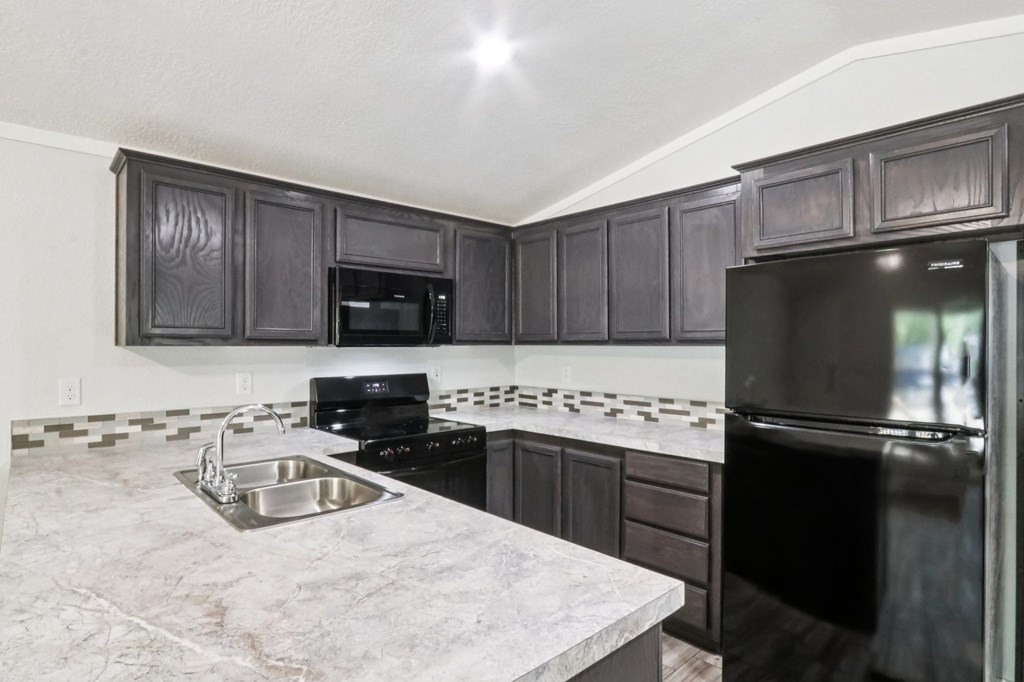 A kitchen with black cabinets and a marble countertop.