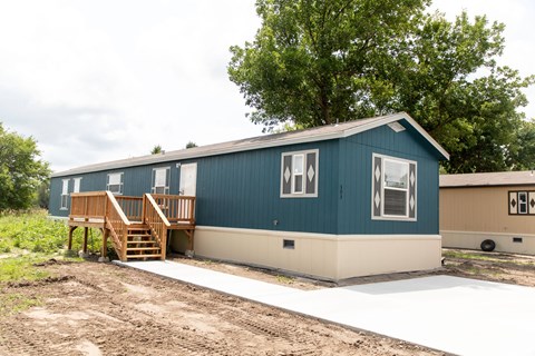 A blue house with a wooden staircase leading to a door.
