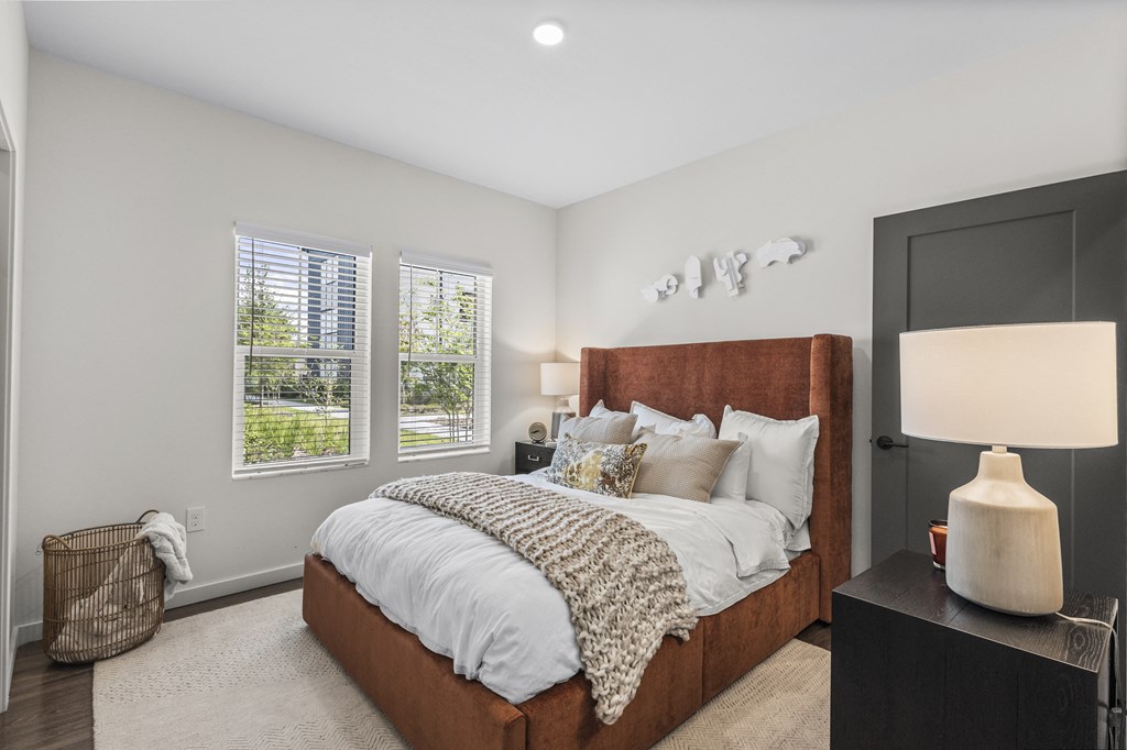 a bedroom with a large bed and two windows