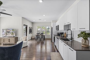 a kitchen and living room with white cabinets and a black counter top