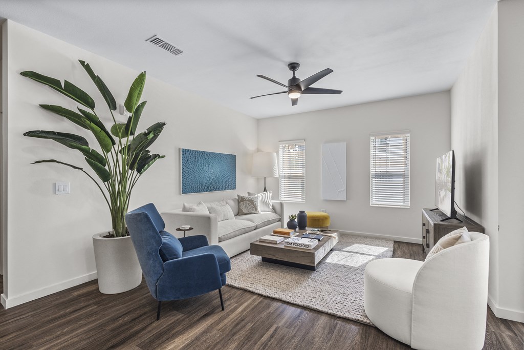 a living room with white furniture and a ceiling fan