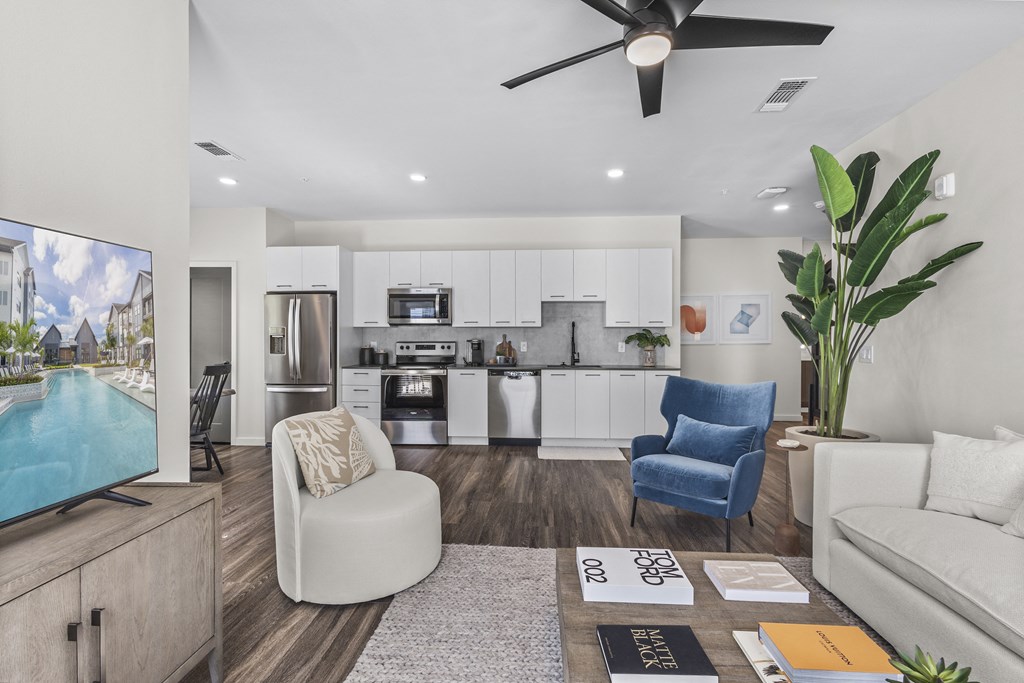 an open living room and kitchen with a pool and a ceiling fan