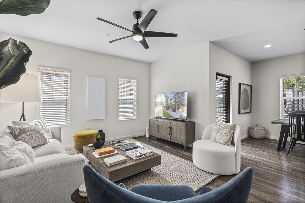 a living room with white walls and a ceiling fan