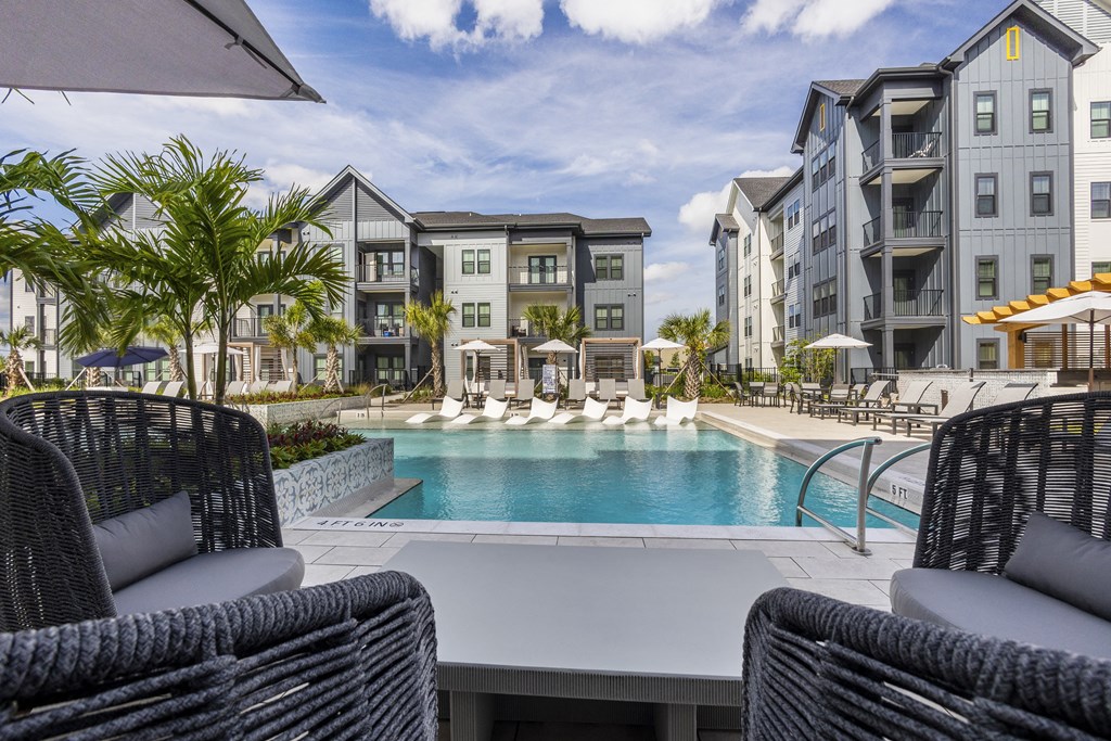a swimming pool with lounge chairs in front of an apartment building