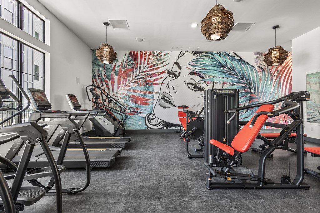 a gym with cardio machines and a mural of a woman on the wall