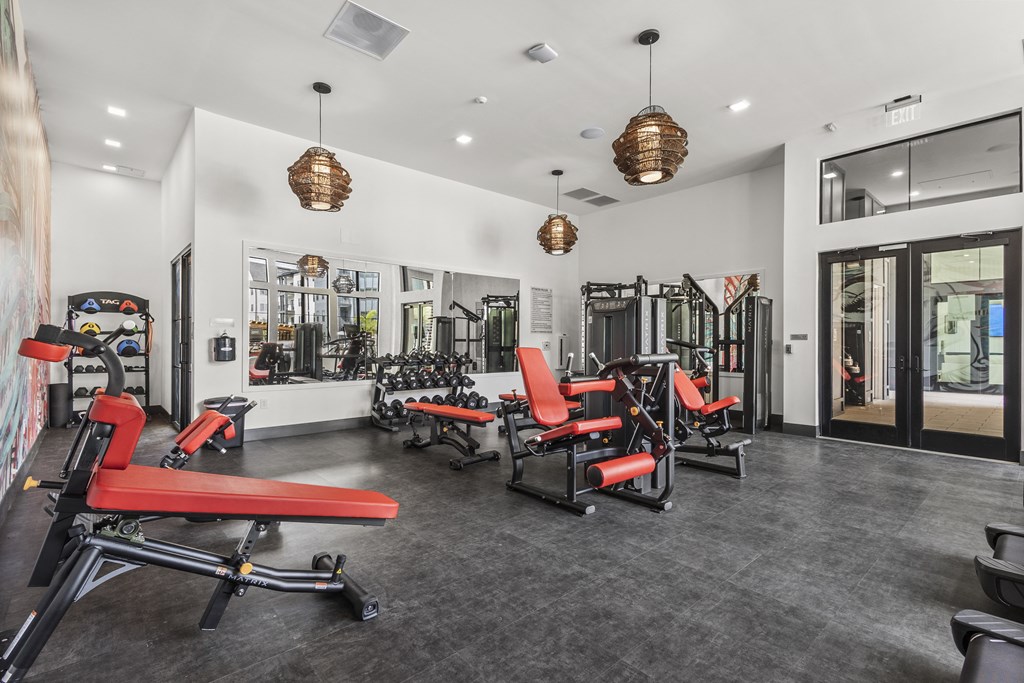 a gym with red chairs and dumbbells and a glass door