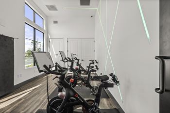 A bike is parked in a room with a white wall and a window.