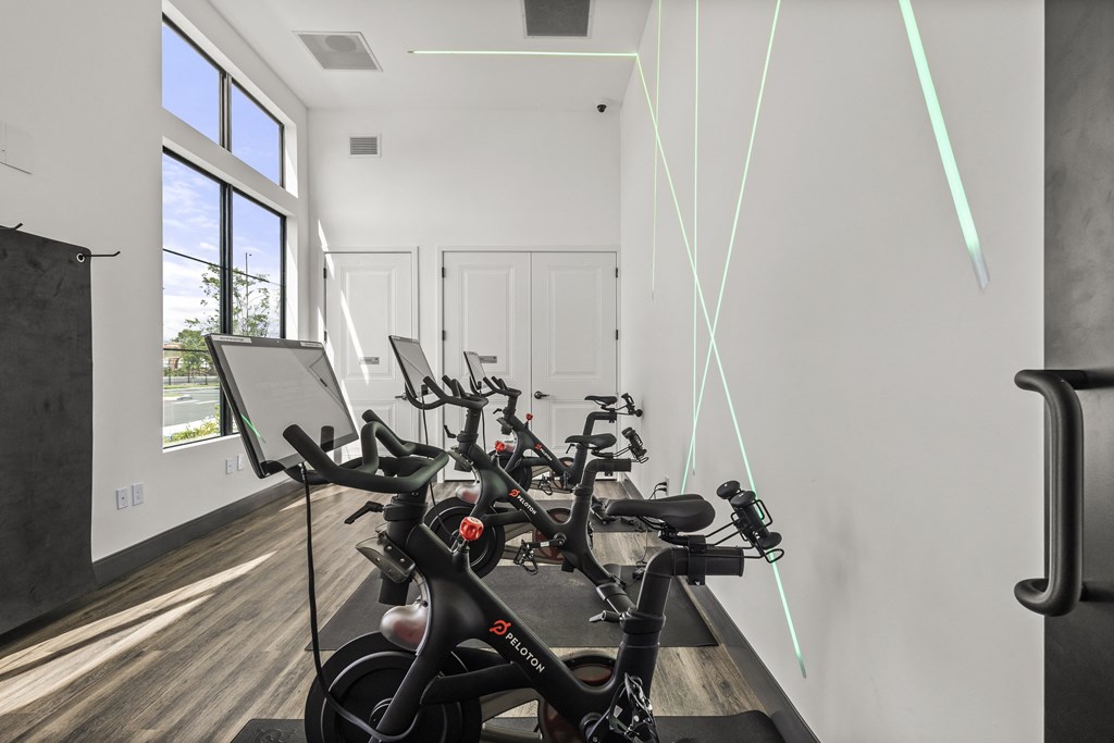 a group of exercise bikes in a room with a wall of windows