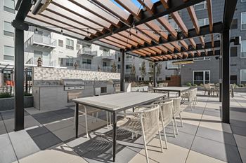 a communal patio with tables and chairs and a grill