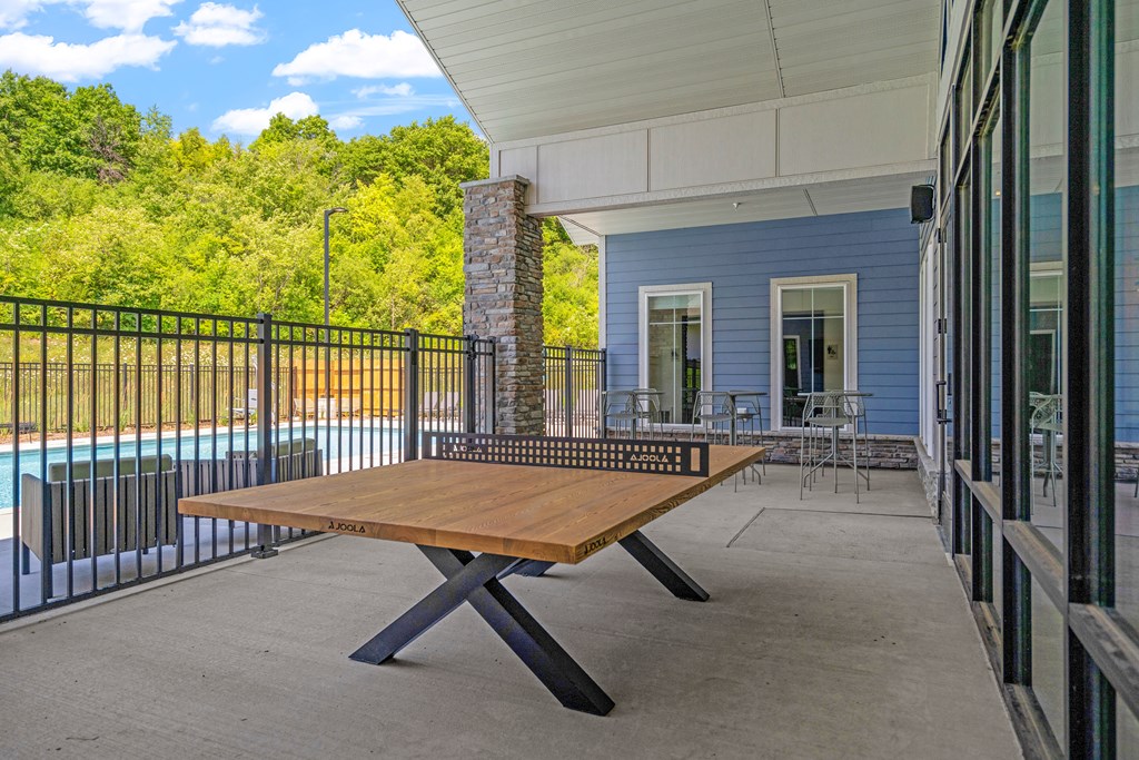 a ping pong table on the patio of a building with a pool in the background at The Lodge at Overland, Rochester, Minnesota