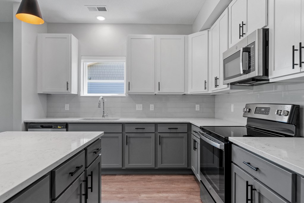 a kitchen with white countertops and gray cabinets at The Lodge at Overland, Rochester, MN
