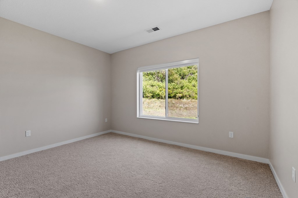a bedroom with a large window and beige carpet at The Lodge at Overland, Minnesota, 55901