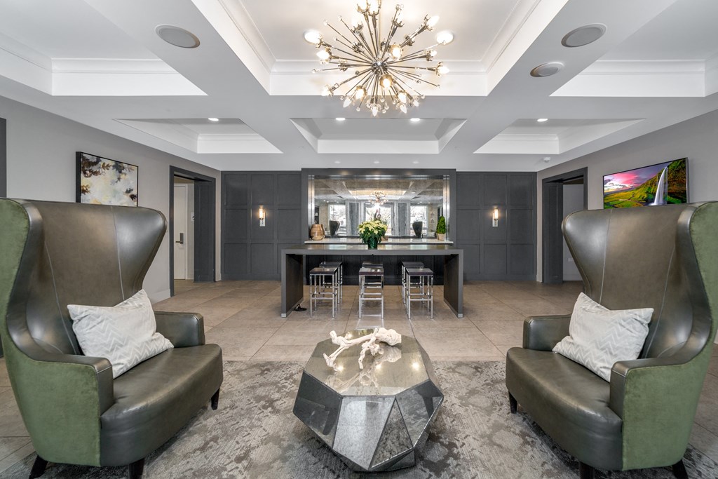 a living room with two leather chairs and a bar and a chandelier