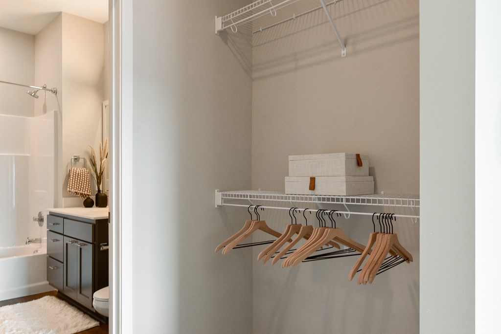 a bathroom with a closet and a rack with wooden hangers at The Hallon Apartments, Minnesota