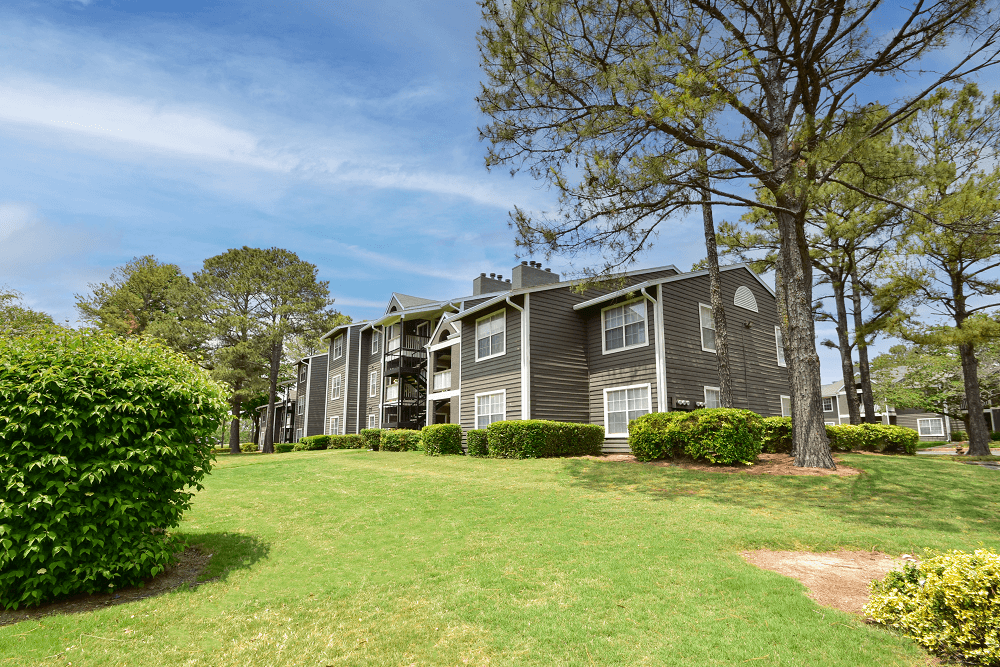 an apartment building on a grassy hill with trees in the background an apartment building on a grassy hill with trees in the background at Riverset Apartments in Mud Island, Memphis, TN