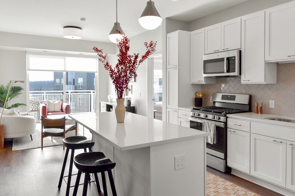 a kitchen with a large white island with three stools at The Hallon Apartments, Minnesota