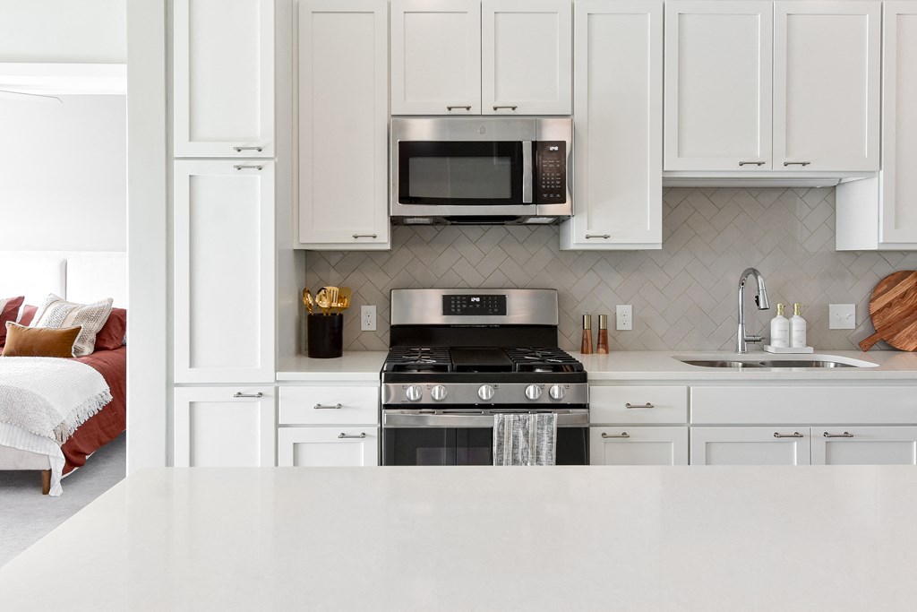a kitchen with white cabinets and a stove and microwave at The Hallon Apartments, Hopkins