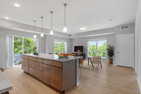 a large kitchen with an island and a living room with a table and chairs