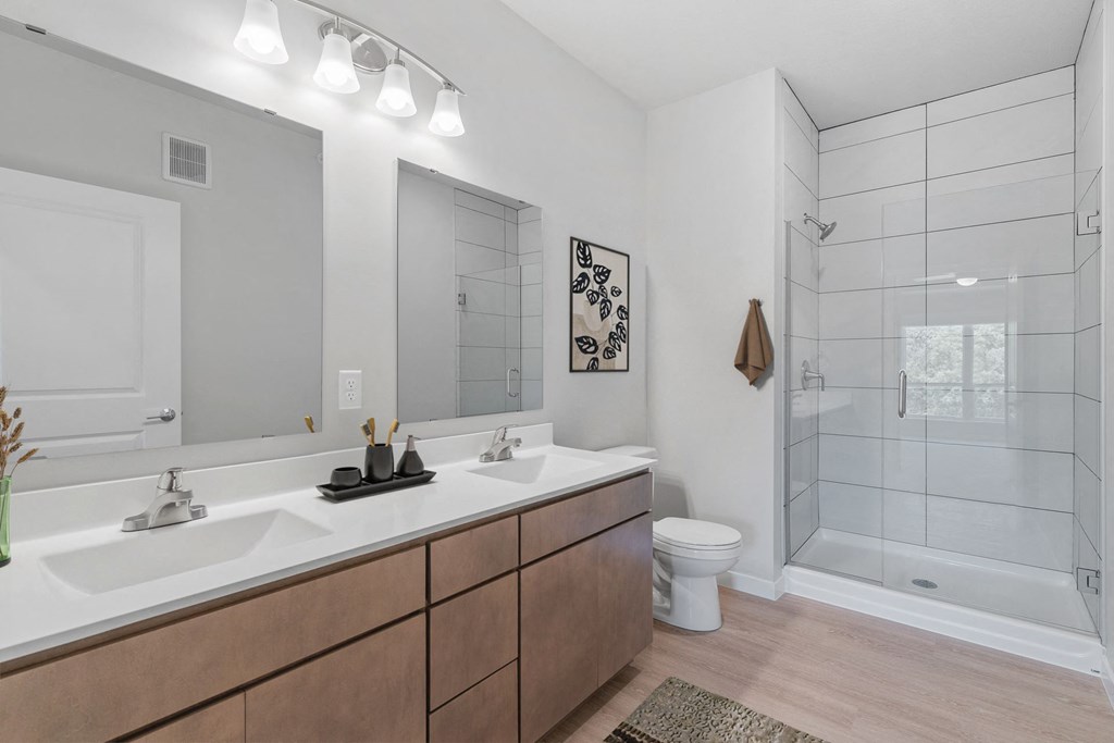a bathroom with two sinks and a shower and a toilet at The Aurilla, Cottage Grove, MN