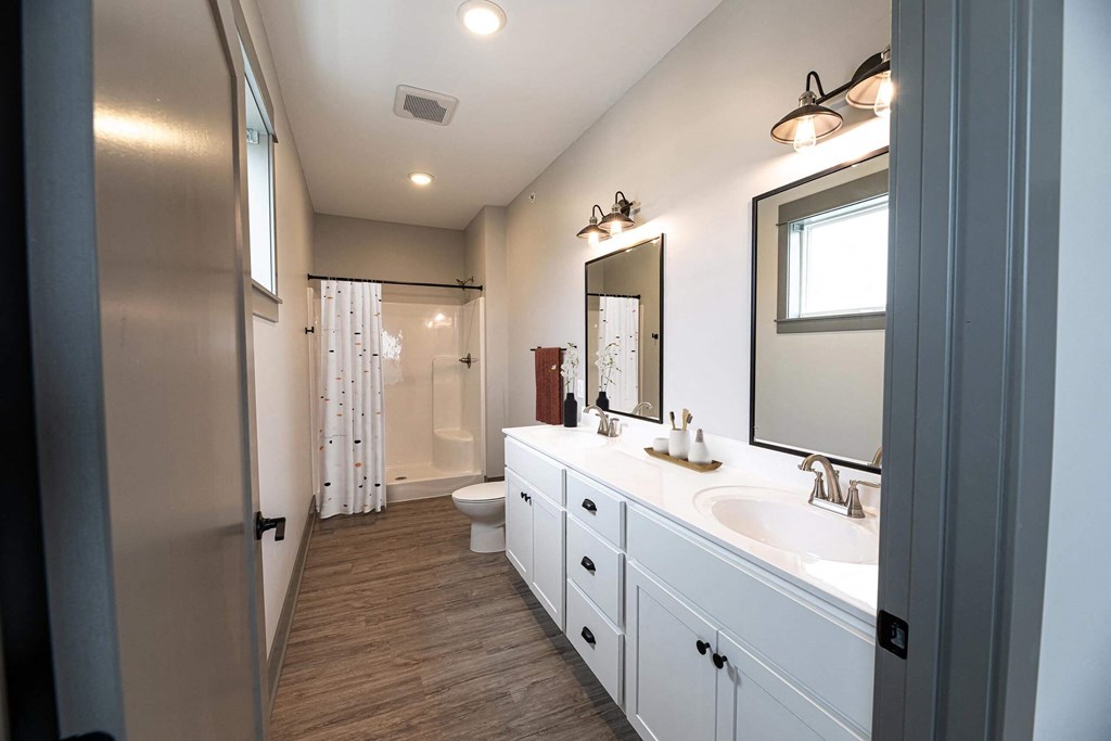 a bathroom with white cabinets and a sink and a toilet at The Commons at Rivertown, Grandville, 49418
