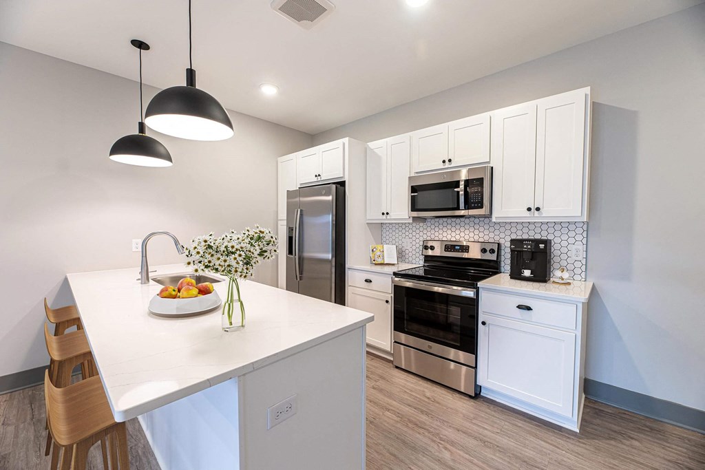 a kitchen with white cabinets and stainless steel appliances at The Commons at Rivertown, Grandville, MI