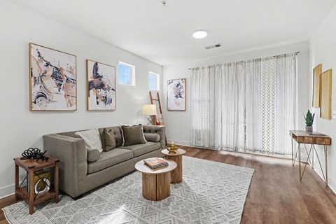 A living room with a grey couch, a coffee table, and a painting on the wall.