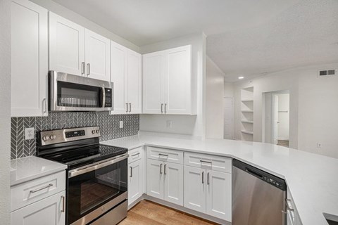 A kitchen with white cabinets and appliances.