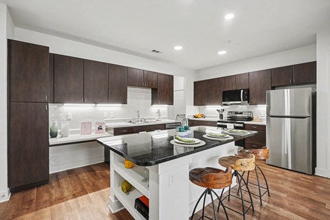 A modern kitchen with dark wood cabinets and stainless steel appliances.
