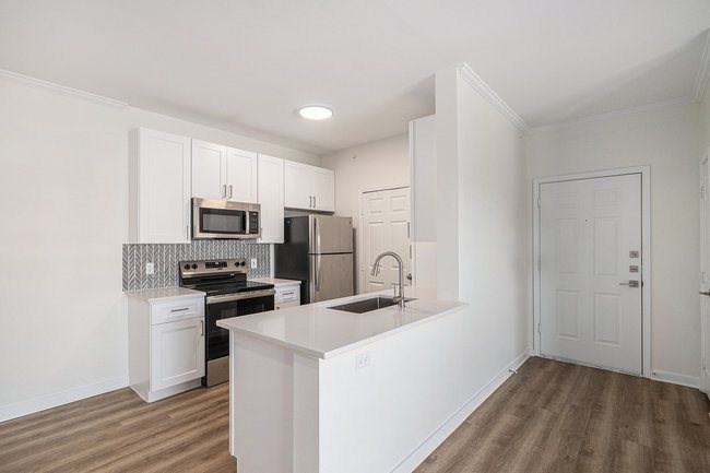 A kitchen with white cabinets and a black fridge.