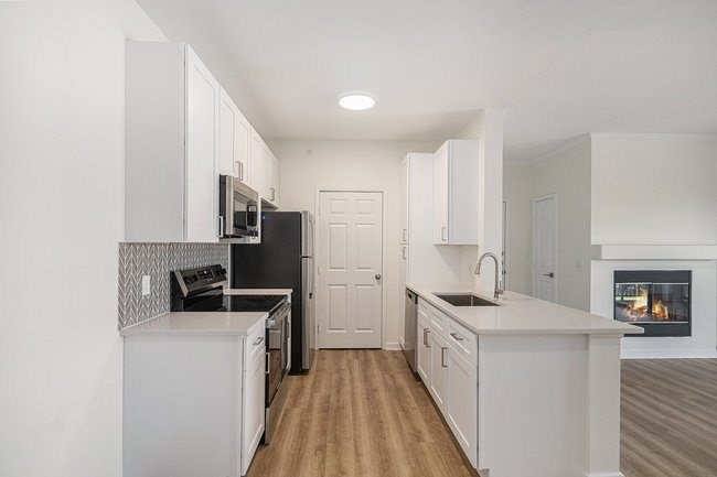 A modern kitchen with white cabinets and a black refrigerator.