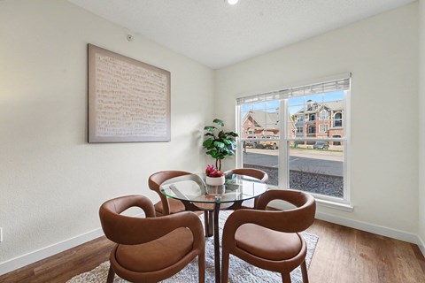A dining room with a table and chairs and a view of the street outside.