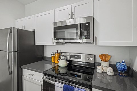 A modern kitchen with a black stove top and white cabinets.
