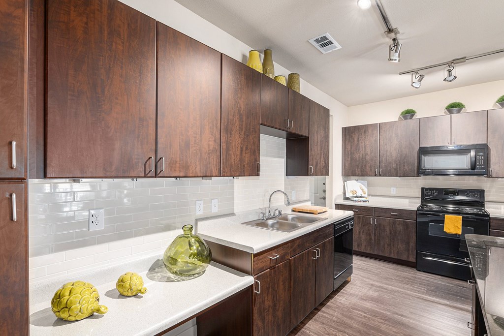 A kitchen with dark wood cabinets and white countertops.